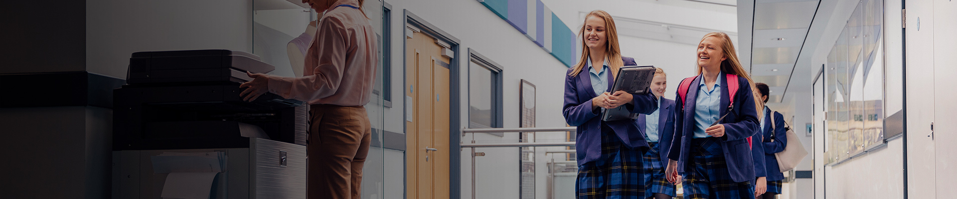 Secondary school students walking down hallway with mobile devices
