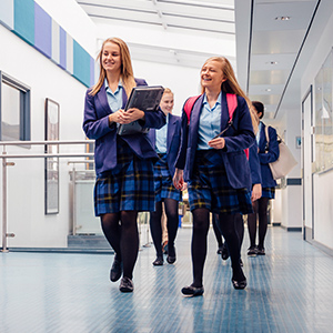 Secondary school students walking down hallway with mobile devices